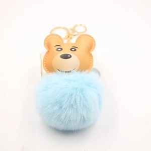 Detailed close-up of a blue faux fur pompom keychain with a cute bear head pendant