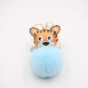 Détail du porte-clés tigre orange avec pompon en fausse fourrure bleue et fermoir doré