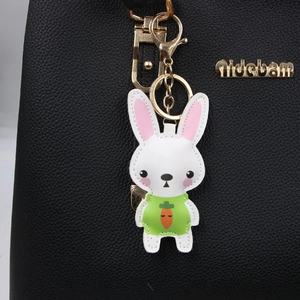 Cartoon white rabbit leather keychain with carrot motif hanging on a black bag