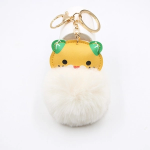 Detail of cartoon tiger plush keychain with white faux fur pompom and golden metal ring