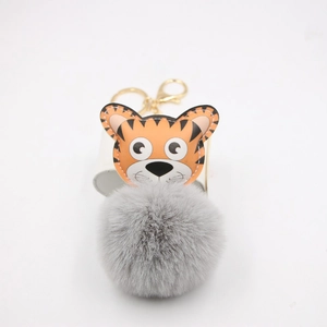 Détail du pendentif tigre en cuir orange avec pompon gris et fermoir mousqueton doré