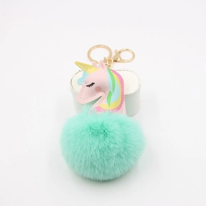 Detail of cute unicorn keychain with mint green faux fur ball and gold metal clasp