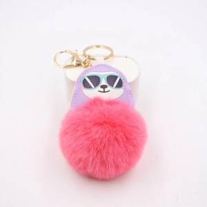 Detail of pink faux fur pompom keychain with a purple sloth wearing sunglasses