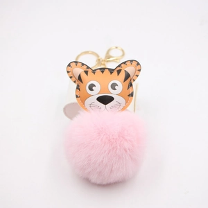 Détail de porte-clés tête de tigre avec pompon rose et fermoir doré en métal