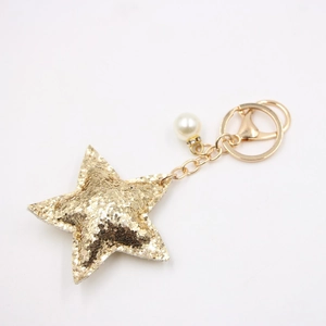 Macro detail of golden glitter star keychain with a faux pearl and lobster clasp