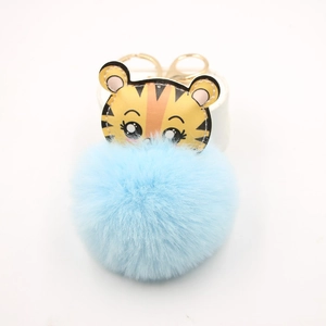 Détail du porte-clés pompon bleu avec tête de tigre jaune et fermoir mousqueton doré