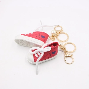 Dettaglio portachiavi sneakers in tela rossa con scritta I Love You e perla decorativa