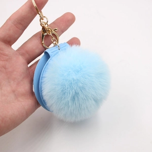 Detail view of light blue faux fur pompom keychain with gold lobster clasp and ring