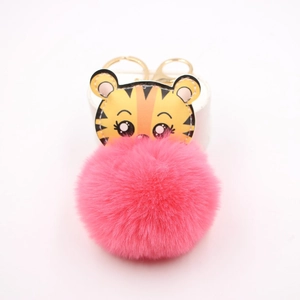 Détail de breloque tigre en cuir avec pompon en fourrure rose et porte-clés doré