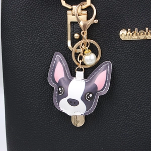 Porte-clés bouledogue français en cuir avec fermoir doré et perle sur un sac noir