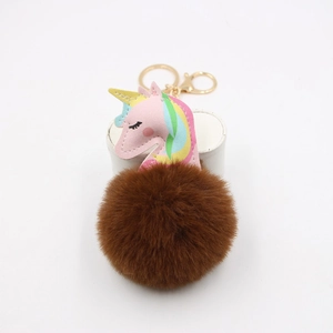 Detail of cute unicorn keychain with a large brown faux fur pompom and gold metal ring
