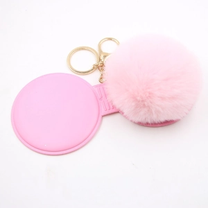 Detail of pink faux fur ball keychain with makeup mirror and golden lobster clasp