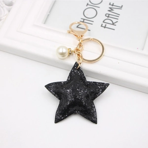 Glittery black star keychain with golden metal clasp and white pearl charm detail