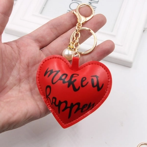 Close-up of red heart leather keychain with white pearl and gold metal hardware