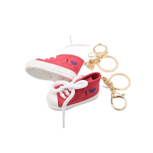 Portachiavi sneaker in tela rossa con suola in gomma bianca e ciondolo di perla