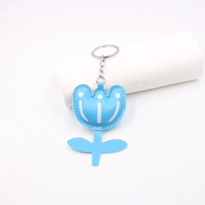 Detail of light blue leather flower keychain with white stitching and silver metal ring