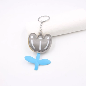 Detail of tulip-shaped leather keychain with blue leaves and white polka dot patterns