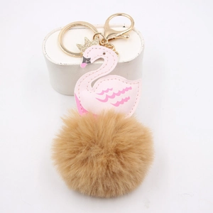Détail d'un porte-clés cygne rose avec couronne dorée et pompon en fausse fourrure brune