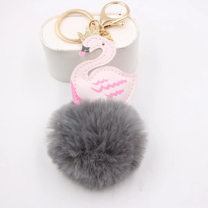 Détail porte-clés cygne en cuir rose avec couronne dorée et pompon en fourrure grise
