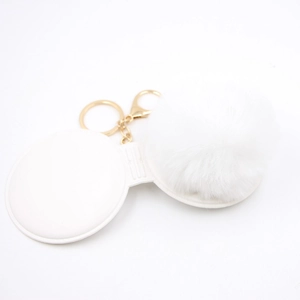 Detail of white fluffy keychain with small makeup mirror and gold metal clasp