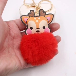 Detail of cute reindeer keychain with faux leather strap and fluffy red fur pompom charm