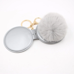 Creative gray pompom makeup mirror keychain with gold hardware on white background