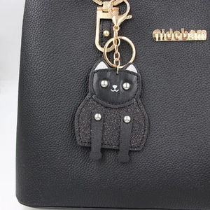 Black lychee leather handbag with a gold logo and cute black cat leather charm accessory
