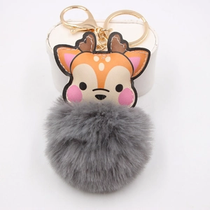 Close-up of cute cartoon deer keychain with gray faux fur pompom and gold lobster clasp