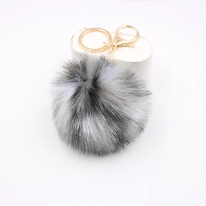 Dettaglio del portachiavi con pompon in ecopelliccia a pois grigio nero bianco e oro