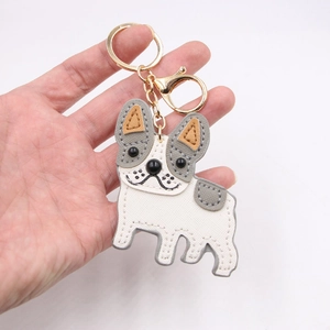 Cute bulldog leather keychain pendant with gold hardware held against white background