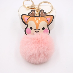 Detail of soft pink faux fur pom pom and painted deer charm on a golden metal keychain