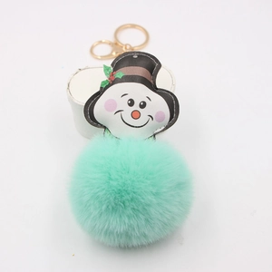 Detailed view of mint green faux fur pompom keychain with festive snowman leather patch