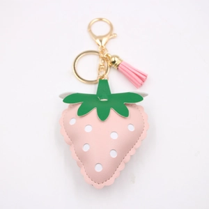 Close-up of strawberry-shaped pink PU leather keychain with white dots and gold lobster clasp