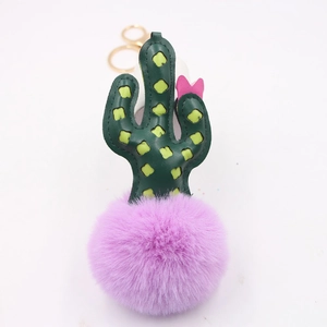 Detail of faux leather cactus keychain featuring pink bow and purple fluffy pompom