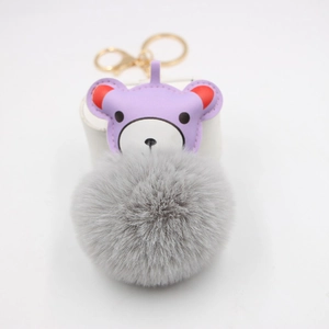 Detail of purple leather bear charm with fluffy grey pompom and gold lobster clasp