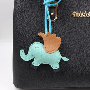 Détail macro du charm éléphant en cuir vert menthe avec ailes brunes sur sac noir grainé
