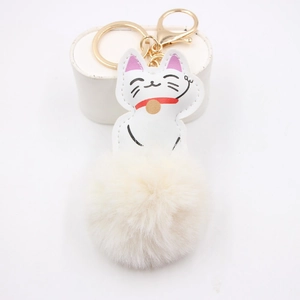 Detail of white Maneki Neko leather charm and soft fluffy pompom keychain with gold ring