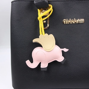 Détail du pendentif éléphant rose sur sac en cuir grainé noir avec logo doré