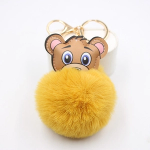 Détail d'un porte-clés tête d'ours brun avec pompon jaune vif et crochet doré brillant