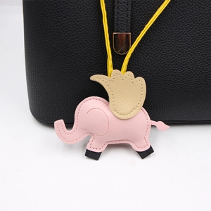 Vue détaillée d'un charm éléphant en cuir rose accroché à un sac à main noir texturé