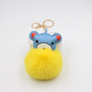 Macro shot of a cute blue leather bear keychain with a bright yellow fluffy pompom
