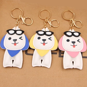 Trois porte-clés chiots en cuir avec lunettes de soleil et écharpes colorées sur carton