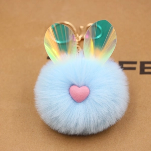 Dettaglio del portachiavi a pompon azzurro con orecchie iridescenti e cuore rosa morbido