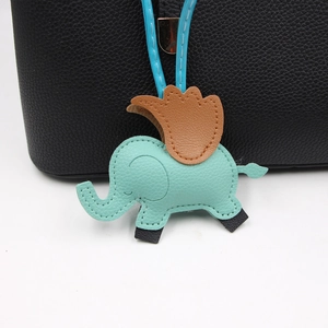 Détail du charm de sac éléphant en cuir vert menthe avec ailes brunes sur un sac noir