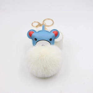 Close-up of cute blue leather bear keychain with soft white faux fur pompom and gold clasp