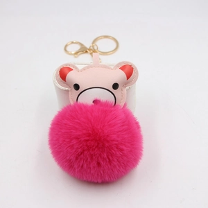 Close-up of pink bear pendant with a large fuchsia pompom and golden metal keychain
