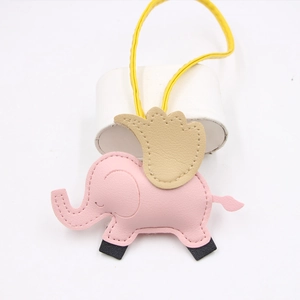 Vue détaillée du charme de sac éléphant en cuir rose avec cordon jaune sur support