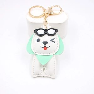 Gros plan d'un porte-clés chien en cuir blanc avec oreilles menthe et fermoir doré chic