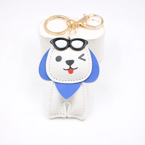 Détail d'un joli porte-clés chien en cuir blanc avec oreilles bleues et fermoir doré