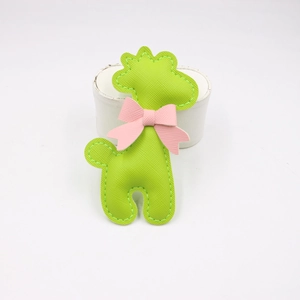 Detail of lime green PU leather giraffe charm featuring a delicate pink bow decoration